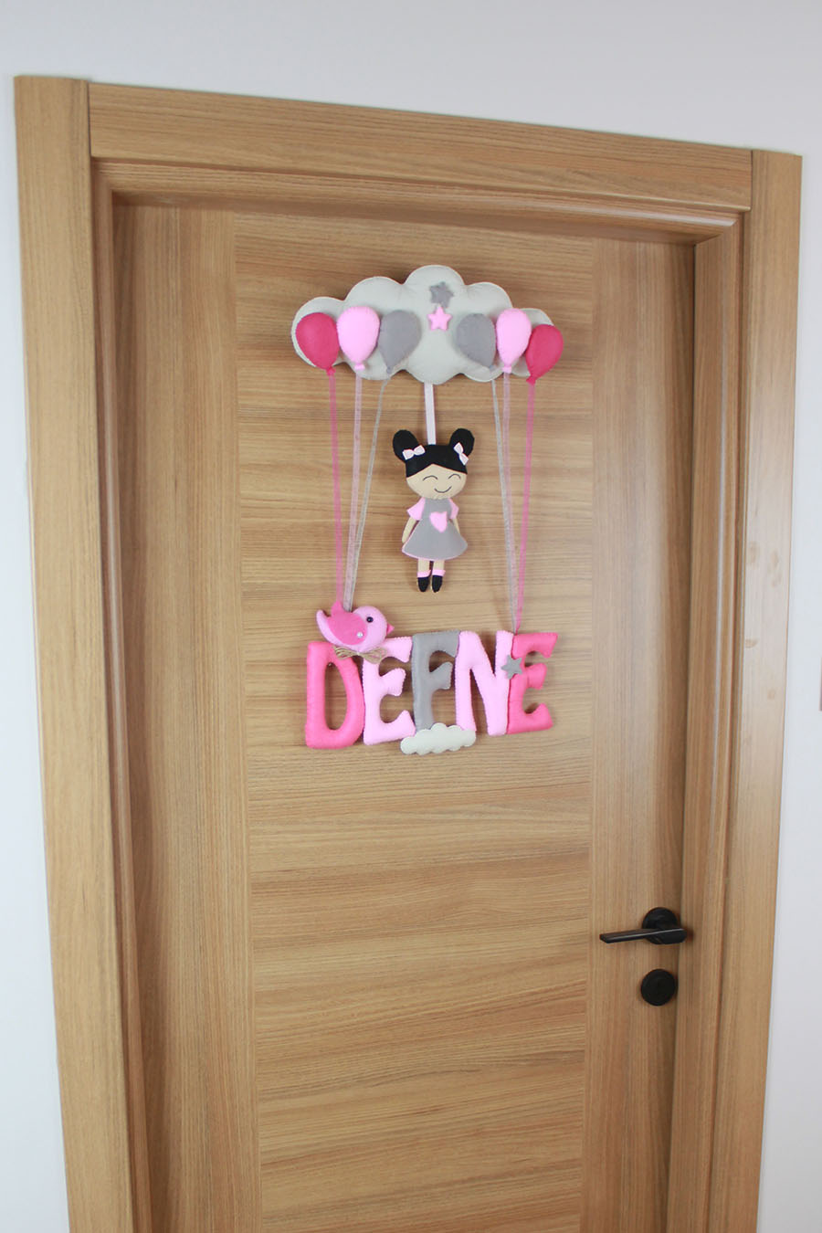 Pembe keçe Defne yazısı ve sallantılı asılış şekli